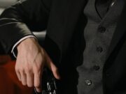 Richard Ramirez: serijski ubica poznat kao Night Stalker i talas straha u Kaliforniji 1985. godine Close-up of a person holding a handgun, exuding a noir and suspenseful vibe.