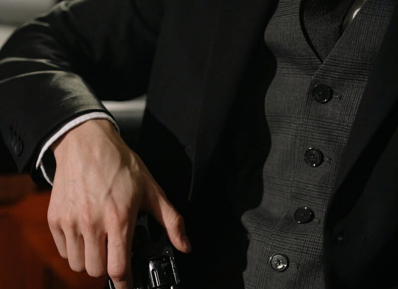 Close-up of a person holding a handgun, exuding a noir and suspenseful vibe.
