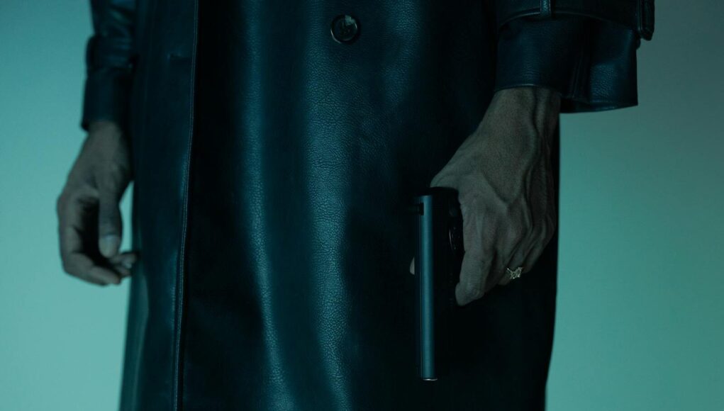 Close-up of an unrecognizable person holding a pistol, creating a mysterious and suspenseful mood.