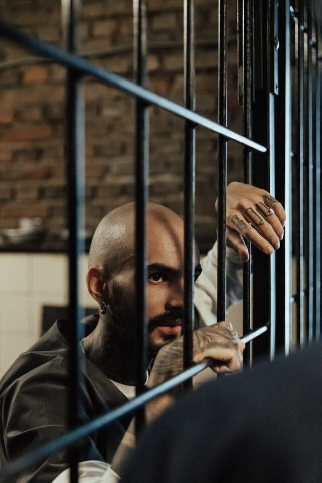 Photo by Ron Lach A tattooed man in a prison cell with a focused expression and visible bars.