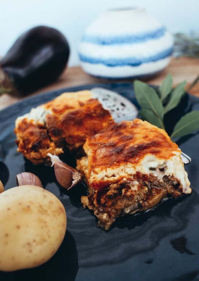 Photo by Rachel Claire Savor the rich layers of vegetable lasagna on a sleek black plate with fresh garlic and potato garnish.