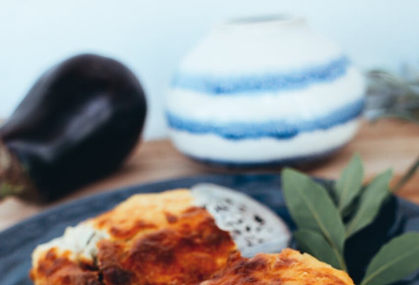 Savor the rich layers of vegetable lasagna on a sleek black plate with fresh garlic and potato garnish.