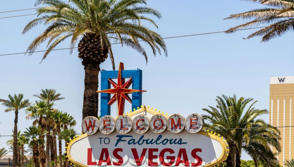 The classic 'Welcome to Las Vegas' sign amidst palm trees, under a bright blue sky.