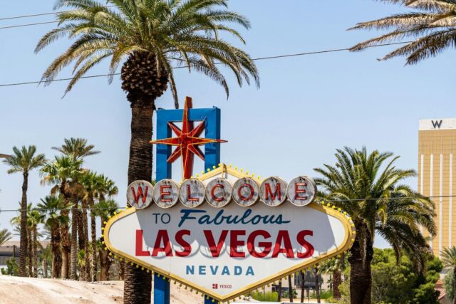 Photo by Abhishek Navlakha The classic 'Welcome to Las Vegas' sign amidst palm trees, under a bright blue sky.