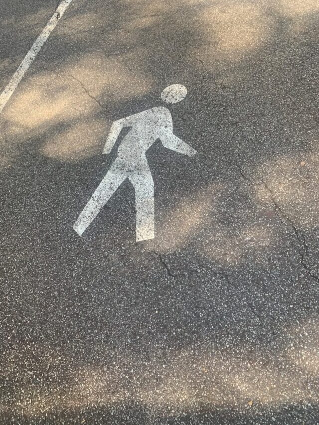 man in black jacket and pants standing on black asphalt road