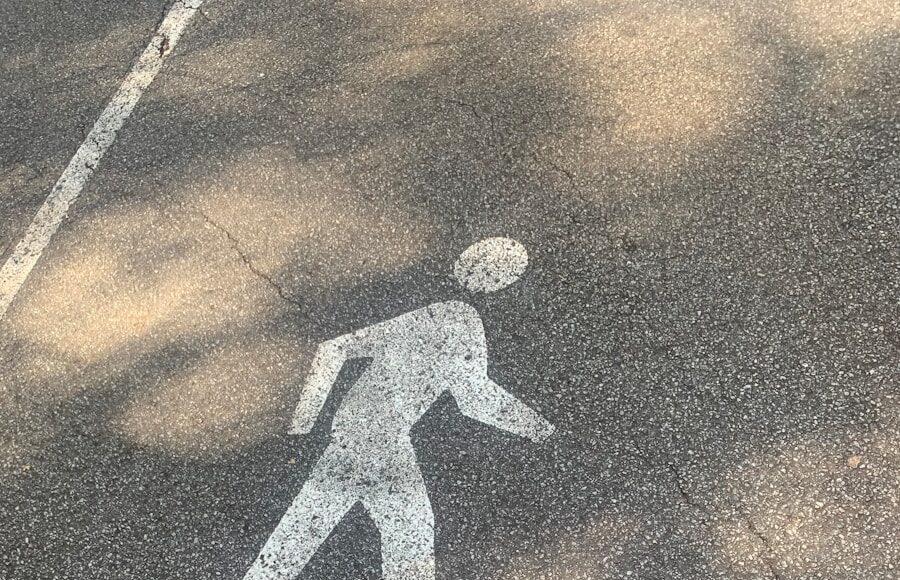 man in black jacket and pants standing on black asphalt road