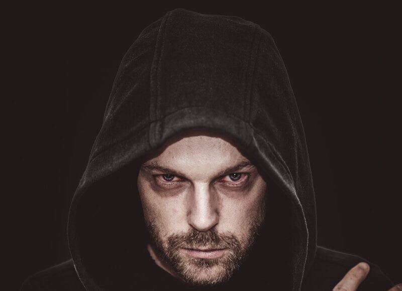 man in black hoodie covering his face with his hand