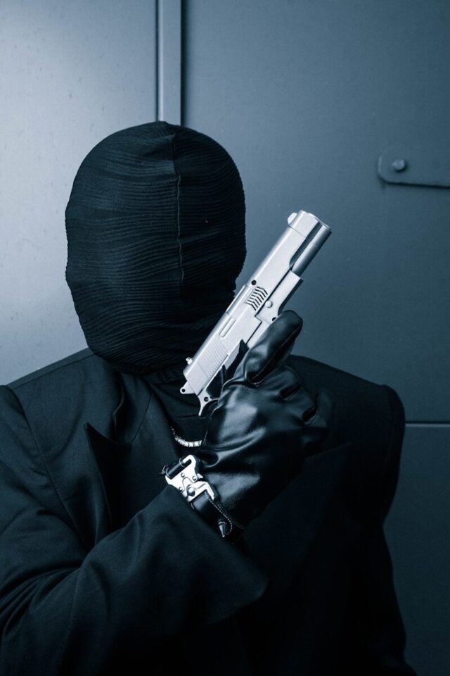 Photo by 1MilliKarat a man in a black suit holding a gun
