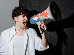 Komšija iz Floride osumnjičen za ubistvo zbog glasne muzike, jedna osoba preminula A man passionately shouting through a decorated megaphone, symbolizing activism.