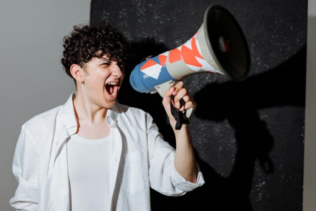 Photo by Thirdman A man passionately shouting through a decorated megaphone, symbolizing activism.