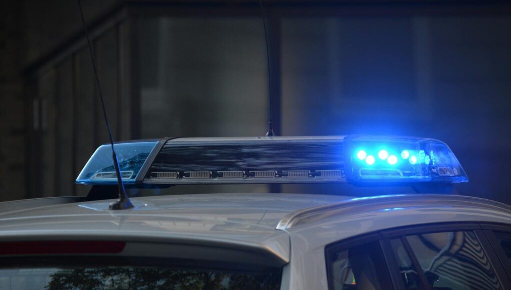 Close-up of a police car's flashing blue lights in an urban environment.