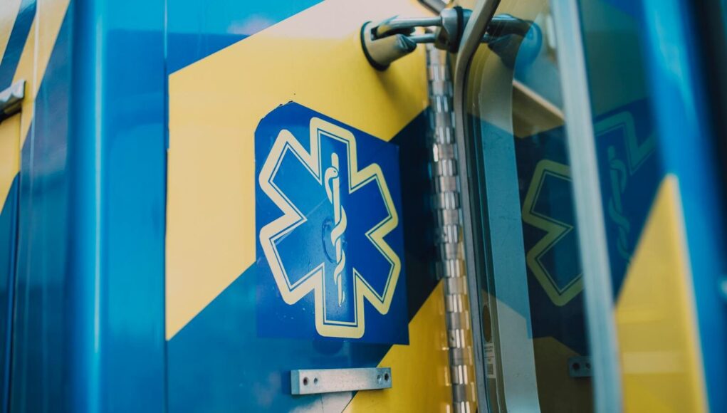 Vibrant blue and yellow medic symbol on an ambulance door, representing emergency medical services.