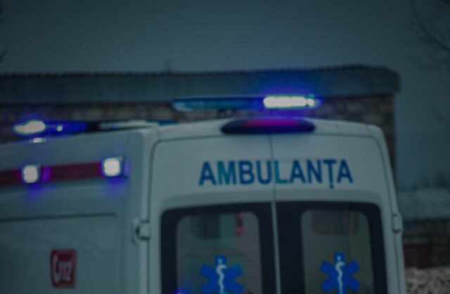 Photo by Gabriel Colta Elderly man walking in front of ambulance on city street during the evening.