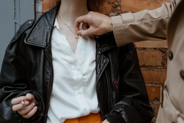 Photo by MART PRODUCTION Close-up of a hand adjusting a necklace on a stylish outfit with a leather jacket.