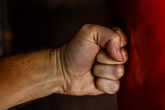 Photo by Pixabay A detailed close-up of a clenched fist striking a red surface showcasing strength.