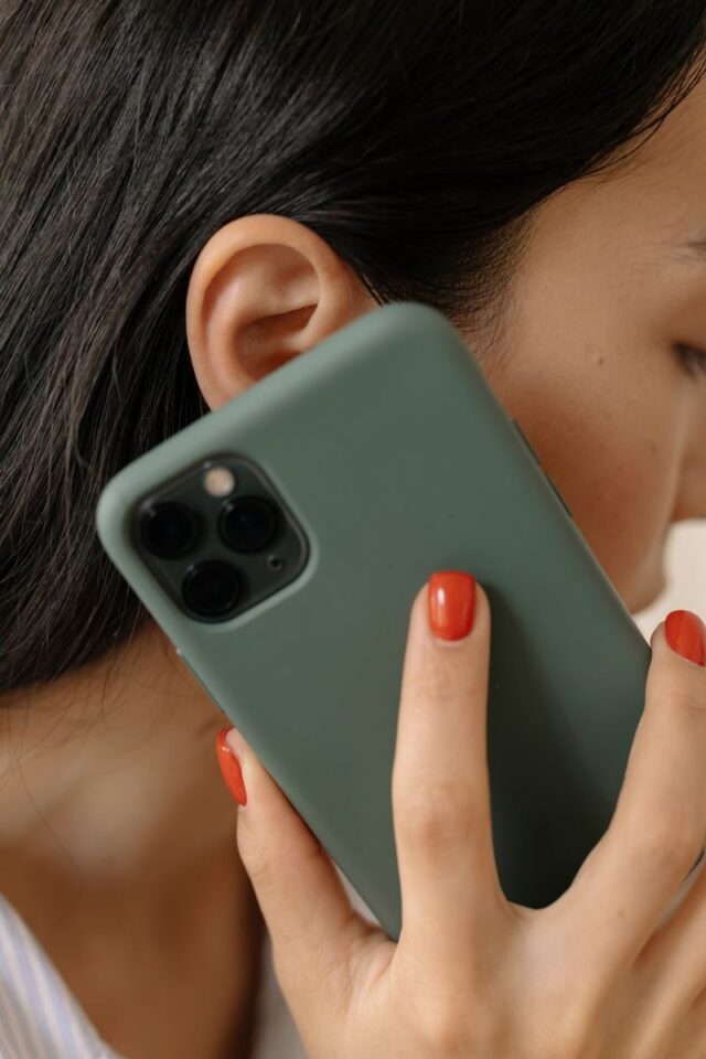 Photo by cottonbro studio A woman with red nails holds a smartphone to her ear, close-up view.
