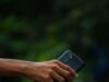Nestao bez traga, a telefon ostao kod kuće: Šta policija prvo proverava kada osoba misteriozno iščezne A person's hand holding a smartphone with a blurred outdoor background, focused view.