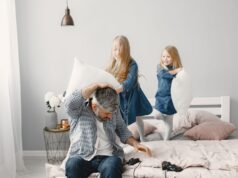 Porodične svađe koje završe pred policijom: Gde prestaje rasprava, a počinje nasilje Father and daughters enjoy a playful pillow fight in a cozy bedroom setting.