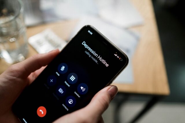 Photo by Ron Lach Close-up of a person holding a smartphone, calling a depression hotline.