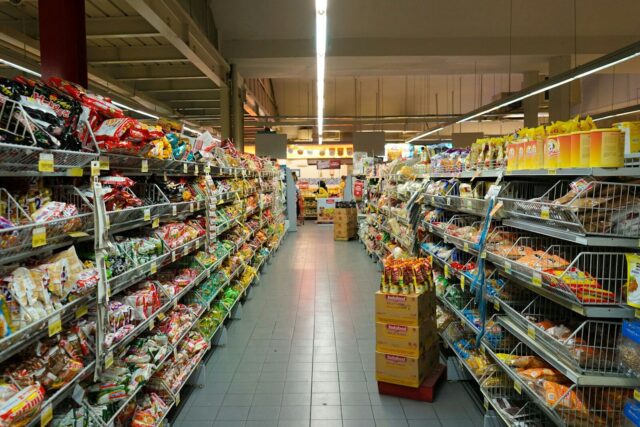 Photo by Fikri Rasyid A grocery store aisle with metal shelves stocked with various packaged food products